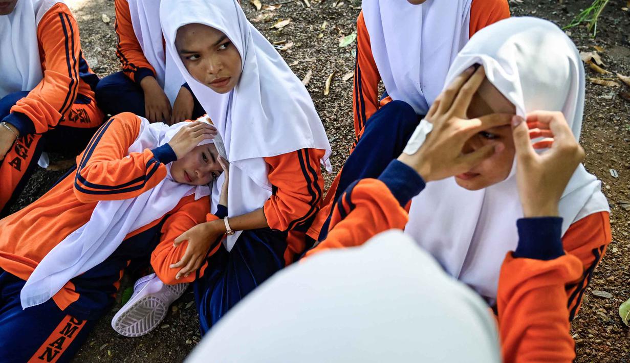 Sejumlah siswa Sekolah Menengah Atas (SMA) mengikuti simulasi gempa bumi dan tsunami untuk memperingati Hari Kesadaran Tsunami Sedunia di Lhoknga, Provinsi Aceh, pada Rabu 5 November 2025. Beberapa skenario mitigasi bencana disimulasikan termasuk penanganan korban luka oleh tim penyelamat atau relawan terlatih. (CHAIDEER MAHYUDDIN/AFP)