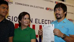 Manny Pacquiao (kanan) menunjukkan Sertifikat Pencalonan Senator  kepada awak media di Mei 2016 pemilihan nasional, di Komisi Pemilihan Umum, Manila, Filipina (16/10/2015). Pacquiao ditemani istrinya Jinkee dan anaknya Michael. (REUTERS/Erik De Castro)