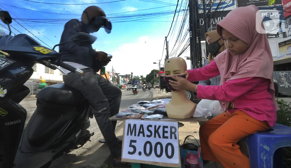 Seorang ibu ditemani anaknya melayani pembeli saat berjualan masker kain buatan rumahan di Jalan Raya Cinere-Depok, Limo, Depok, Rabu (8/4/2020).  Anjuran pemerintah mengenai penggunaan masker kain dimanfaatkan ibu ini untuk berjualan masker kain. (merdeka.com/Arie Basuki)