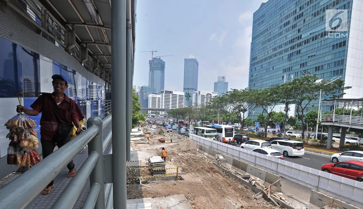 Pejalan kaki melintas di jembatan penyeberangan dekat proyek penataan ulang trotoar Jalan Jenderal Sudirman, Jakarta, Kamis (25/10). Pejalan kaki harus memutar ketika turun dari jembatan penyeberangan melalui jalur khusus. (Merdeka.com/Iqbal Nugroho)