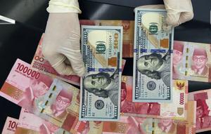 Karyawan menunjukkan uang dolar AS dan rupiah di Jakarta, Rabu (30/12/2020). Nilai tukar rupiah di pasar spot ditutup menguat 80 poin atau 0,57 persen ke level Rp 14.050 per dolar AS. (Liputan6.com/Johan Tallo)