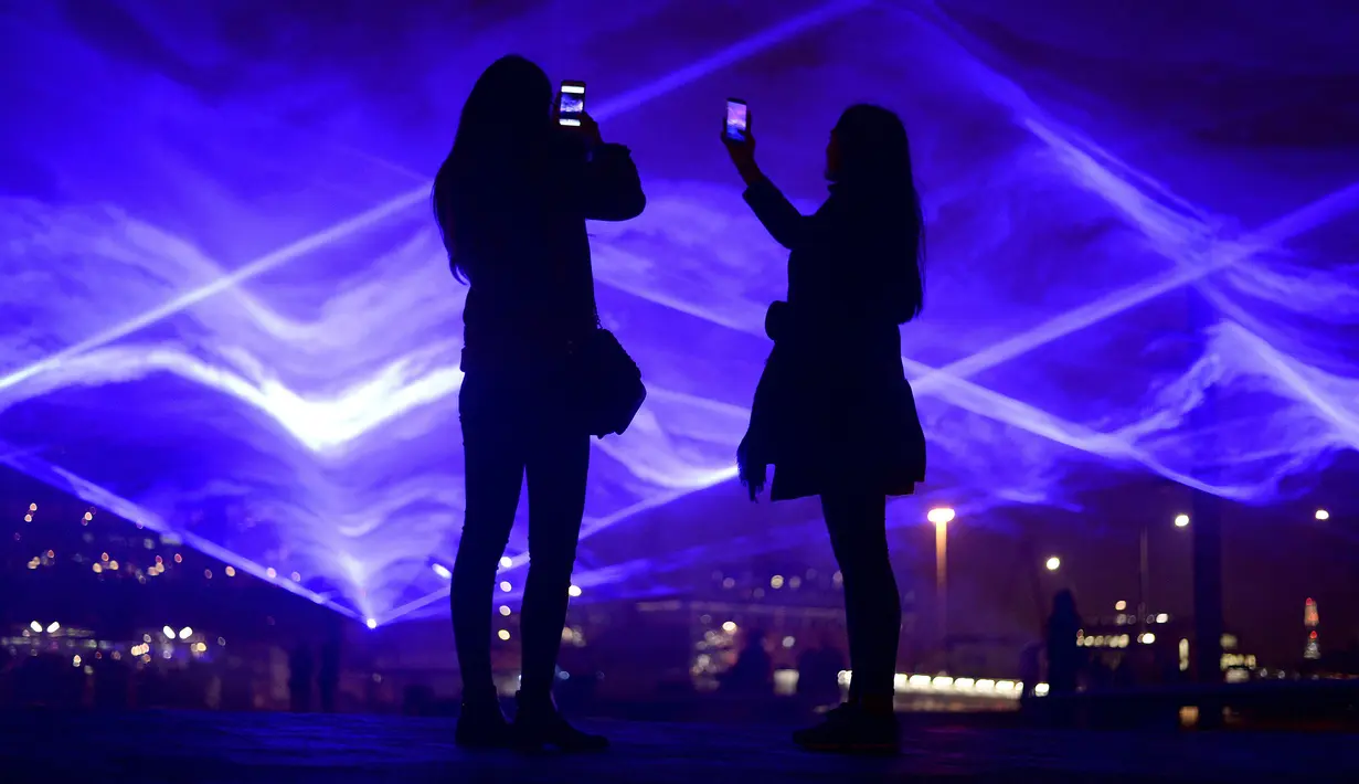 Sejumlah pengunjung mengambil foto karya seni yang berjudul Waterlicht dari seniman Daan Roosegaarde saat festival cahaya Lumiere London di Granary Square di London (17/1). (Kirsty O'Connor / PA via AP)