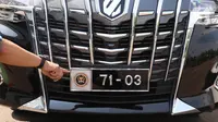 Seorang petugas menunjukan logo pada kendaraan dengan plat nomor khusus anggota DPR yang terparkir di Kompleks Parlemen, Senayan, Jakarta, Selasa (25/5/2021).  Penggunaan plat nomor khusus tersebut hanya menyempurnakan penggunaan atribut logo DPR. (Liputan6.com/Angga Yuniar)