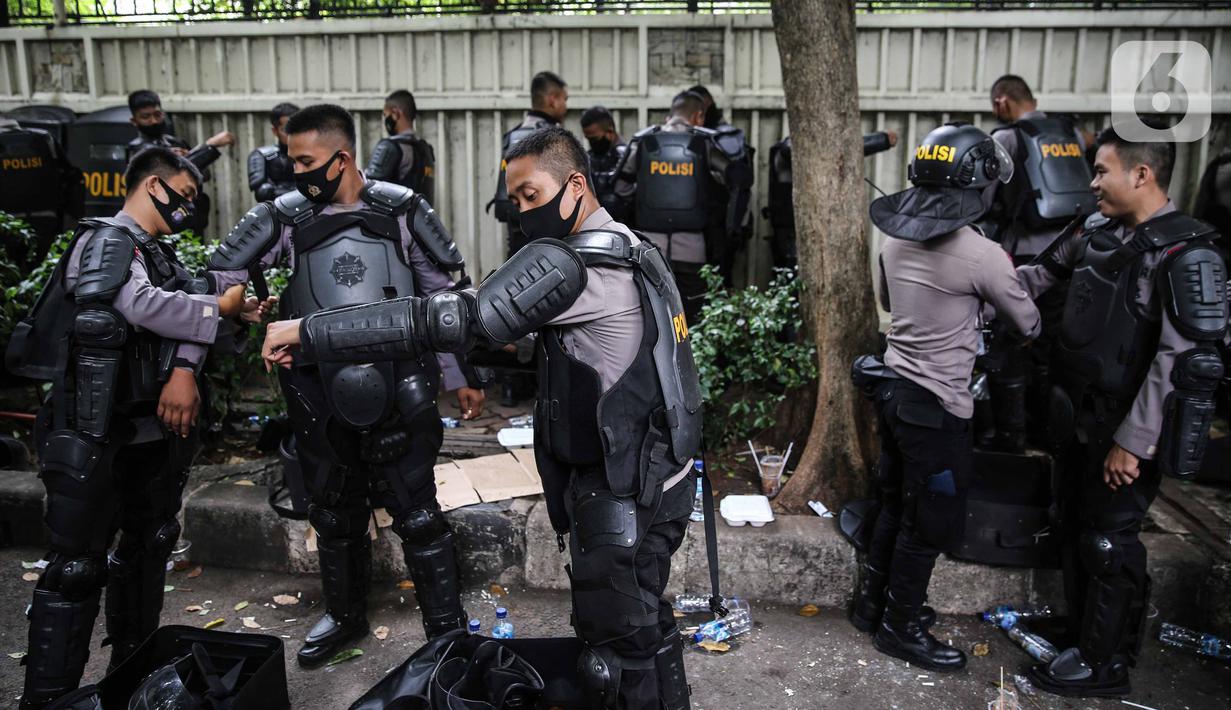 Personel Brimob bersiap mengenakan perlengkapan pelindung diri di Kawasan Bundaran HI, Jakarta, Selasa (13/10/2020). Sebanyak kurang lebih 12 ribu personel gabungan TNI, Polri dan Pemprov DKI Jakarta diterjunkan mengawal aksi tolak Undang-Undang Cipta Kerja Omnibus Law. (Liputan6.com/Faizal Fanani)