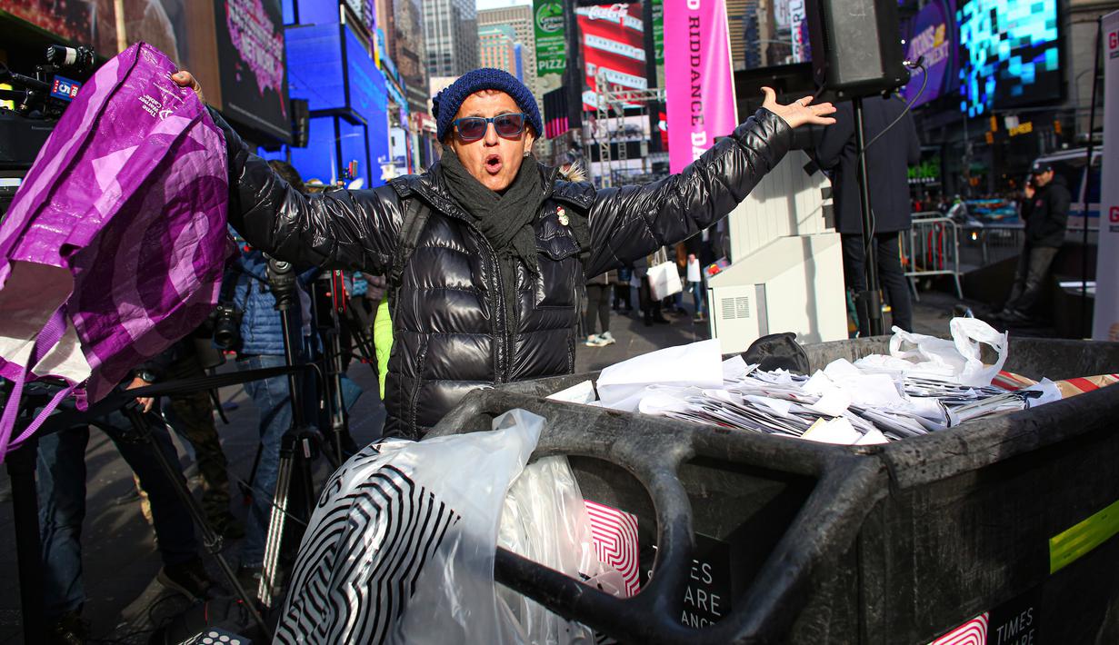 Reaksi seorang perempuan setelah melempar kertas-kertas berisi kenangan buruk ke tempat sampah selama Good Riddance Day ke-13 tahunan di Times Square, New York, 28 Desember 2019. Kegiatan menjelang tahun baru itu menjadi tradisi untuk menghapus kenangan buruk selama satu tahun. (Kena Betancur / AFP)