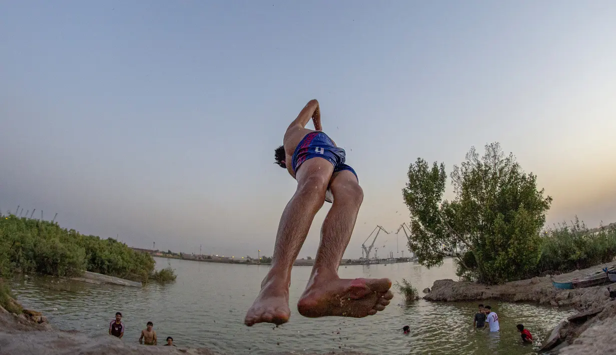 Seorang pemuda terjun ke Sungai Shatt Al-Arab di Kota Basra, Irak, Selasa (9/6/2020). Sungai yang memiliki panjang sekitar 200 Km ini menandai perbatasan antara Irak dan Iran. (Hussein FALEH/AFP)