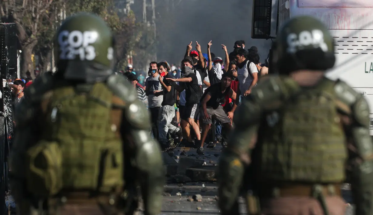Demonstran saat bentrok dengan polisi di tengah pandemi virus corona Covid-19 selama penguncian wilayah (lockdown) di lingkungan miskin di Santiago, Chili, (18/5/2020). Demonstrasi tersebut berujung kerusuhan. (AP Photo/Esteban Felix)