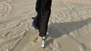 Azizah mengenakan dress hitam dipadukan outer warna serasi saat berkunjung ke gurun pasir. Ia juga mengenakan sorban di atas kepalanya. [@azizahsalsha_]