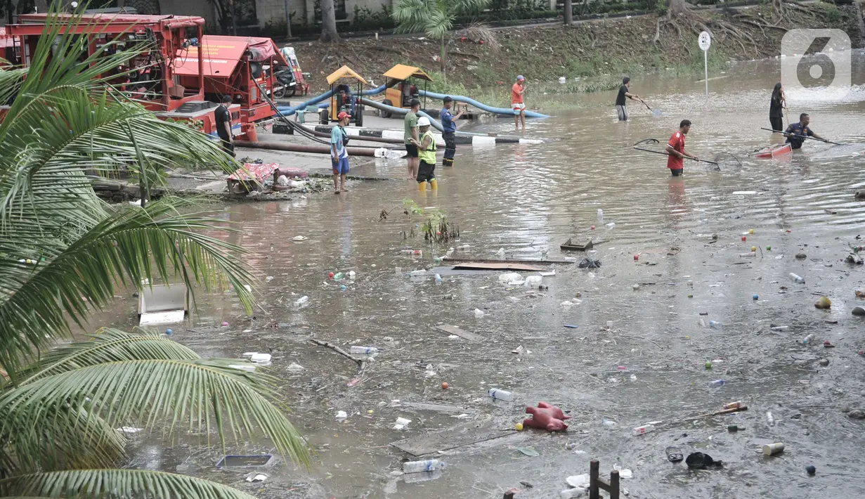 Petugas Pusat Pengelolaan Kompleks (PPK) Kemayoran membersihkan sampah yang muncul akibat banjir di Underpass Kemayoran, Jakarta, Minggu (2/2/2020). Selain melumpuhkan akses, banjir setinggi hingga 5 meter tersebut menyebabkan sampah memenuhi Underpass Kemayoran. (merdeka.com/Iqbal S. Nugroho)