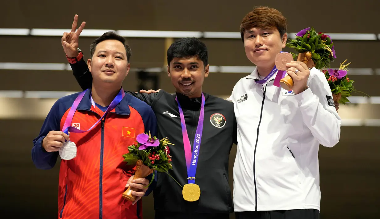 Peraih medali emas Muhammad Sejahtera Dwi Putra dari Indonesia (tengah) berpose dengan peraih medali perak Huu Vuong Ngo dari Vietnam, kiri, dan peraih medali perunggu Youjin Jeong dari Korea Selatan dalam upacara penghargaan cabang olahraga menembak nomor 10 meter lari jarak jauh putra di Fuyang Yinhu Sports Centre pada Asian Games ke-19 di Hangzhou, China, Senin, 25 September 2023. (AP Photo/Aijaz Rahi)