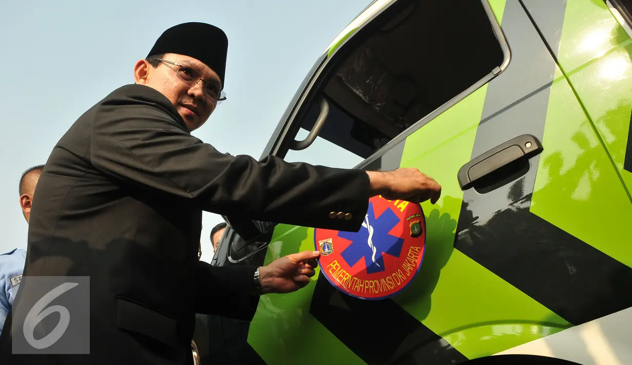 Basuki T Purnama menempelkan stiker di mobil ambulan saat peluncuran bus-bus baru dan hotline Transjakarta di monas, Jakarta, Senin (22/6/2015). Sebanyak 20 unit bus gandeng Transjakarta buatan eropa resmi diluncurkan. (Liputan6.com/Herman Zakharia)