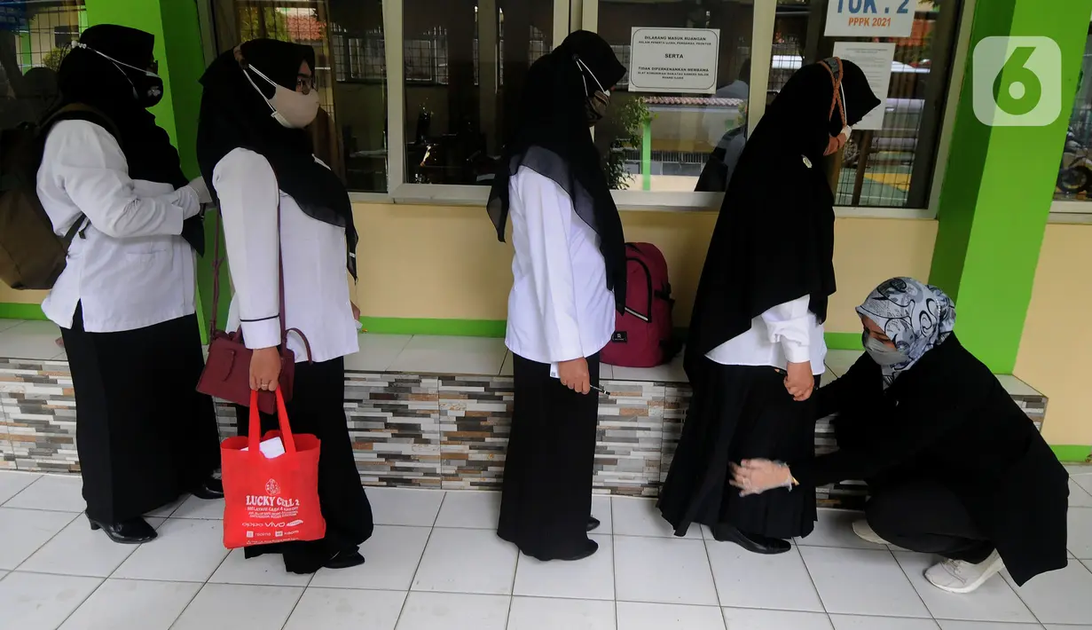 Peserta diperiksa seluruh badannya sebelum pelaksanaan ujian seleksi kompetensi P3K Guru di SMKN 2, Depok, Jawa Barat, Selasa (14/9/2021). Kemendikbud mulai Senin (13/9) secara serentak di Indonesia dilaksanakan ujian Seleksi Kompetensi P3K yang tersebar di 1000 lokasi. (merdeka.com/Arie Basuki)