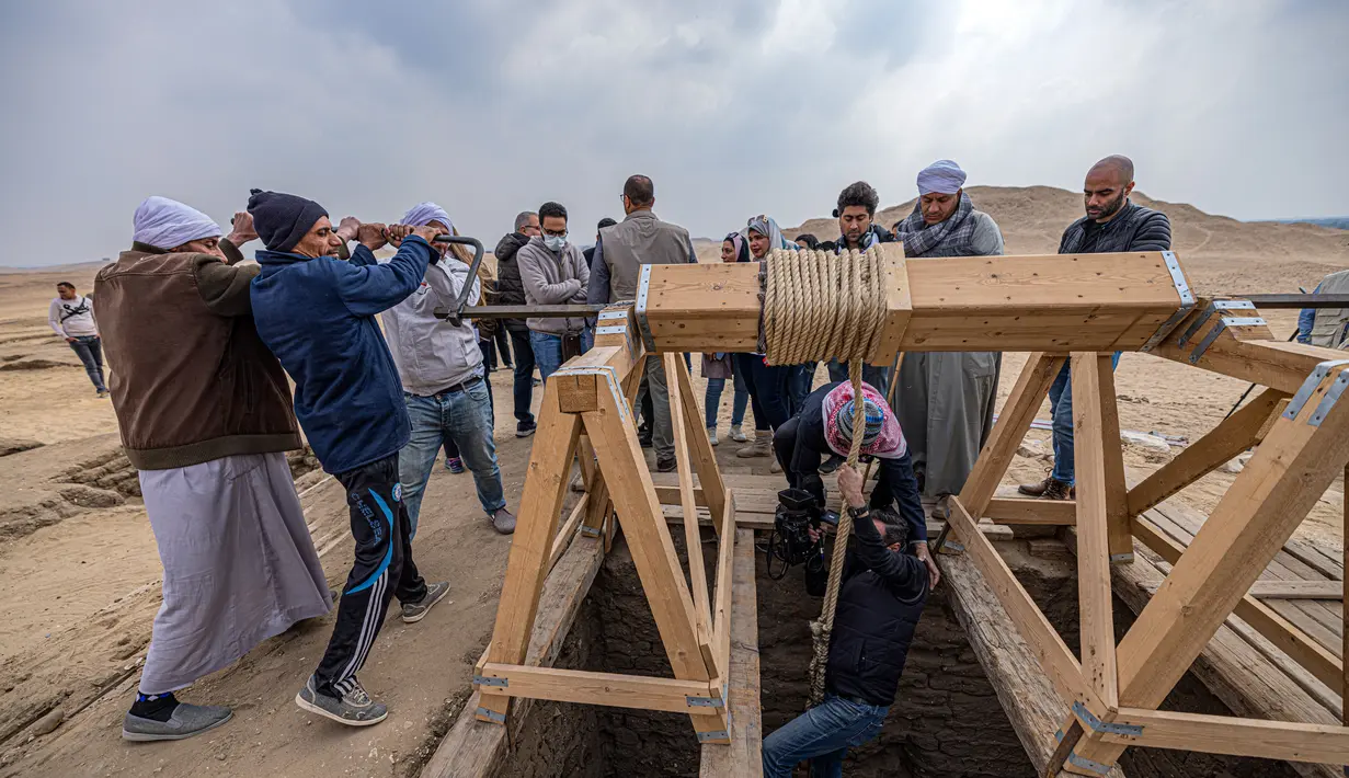 Seorang anggota media turun ke salah satu dari lima makam Firaun kuno yang ditemukan di situs arkeologi Saqqara, Kairo, Mesir(19/3/2022). Menurut Waziri, lima makam yang semuanya dalam kondisi baik itu milik petinggi kerajaan. (AFP/Khaled Desouki)
