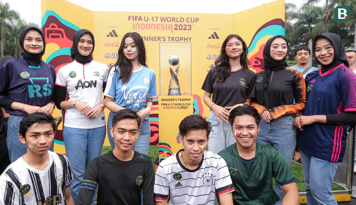 Para peserta kegiatan menggiring bola raksasa melakukan foto bersama trofi Piala Dunia U-17 dalam rangkaian acara Trophy Experience menyambut Piala Dunia U-17 2023 di Plaza Upakarti, Soreang, Kabupaten Bandung, Minggu (22/10/2023) sore WIB. (Bola.com/Bagaskara Lazuardi)