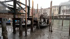 Penumpang turun dari gondola yang berlabuh di sepanjang kanal saat air surut di Venesia, Italia, 21 Februari 2023. Beberapa kanal sekunder Venesia praktis mengering akhir-akhir ini akibat gelombang surut terkait dengan sistem cuaca bertekanan tinggi yang berkepanjangan. (AP Photo/Luigi Costantini)