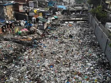 Pandangan udara menunjukkan anak-anak berdiri di dekat saluran pembuangan air yang dipenuhi sampah di lingkungan berpenghasilan rendah di New Delhi, India (4/10/2019). (AFP Photo/Noemi Cassanelli)