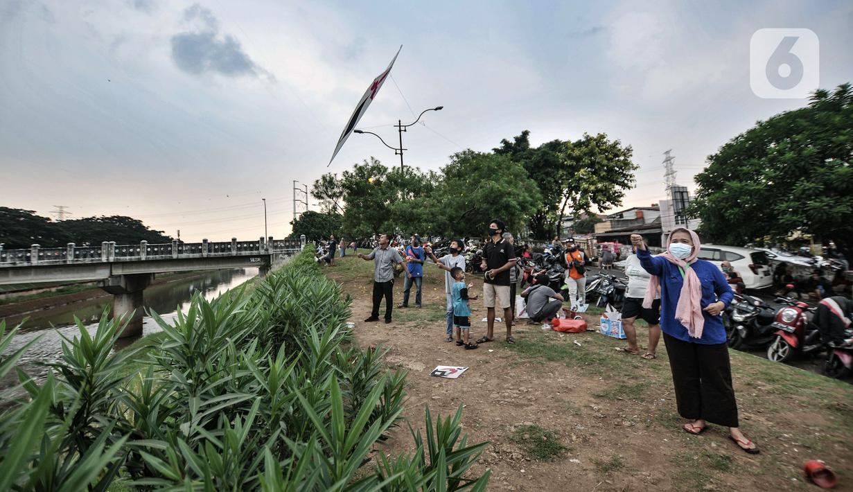 Warga bermain layang-layang di pinggir Kanal Banjir Timur (KBT), Duren Sawit, Jakarta, Senin (19/4/2021). KBT menjadi lokasi favorit warga untuk mengisi waktu menunggu buka puasa atau ngabuburit, salah satunya dengan bermain layang-layang bersama keluarga. (merdeka.com/Iqbal S Nugroho)