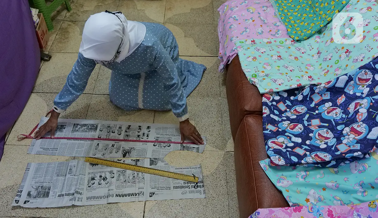 Penjahit sedang membuat pola Gown di kawasan Cipinang Cempedak, Jakarta, Kamis (18/6/2020). Kreasi penutup kepala, masker dan Gown yang di inisiasi oleh seorang dokter di RSIA Tambak yang di design untuk khusus tema anak saat masa Pandemi  COVID-19. (Liputan6.com/Herman Zakharia)