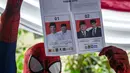 Petugas Kelompok Penyelenggara Pemungutan Suara (KPPS) berkostum superhero Spiderman menunjukkan surat suara Pemilu 2019 di sebuah TPS di Surabaya, Jawa Timur, Rabu (17/4). (Juni Kriswanto/AFP)