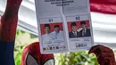 Petugas Kelompok Penyelenggara Pemungutan Suara (KPPS) berkostum superhero Spiderman menunjukkan surat suara Pemilu 2019 di sebuah TPS di Surabaya, Jawa Timur, Rabu (17/4). (Juni Kriswanto/AFP)