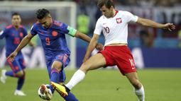 Striker Kolombia, Radamel Falcao, berusaha melewati gelandang Polandia, Grzegorz Krychowiak, pada laga grup H Piala Dunia di Kazan Arena, Kazan, Minggu (24/6/2018). Kolombia menang 3-0 atas Polandia. (AP/Thanassis Stavrakis)