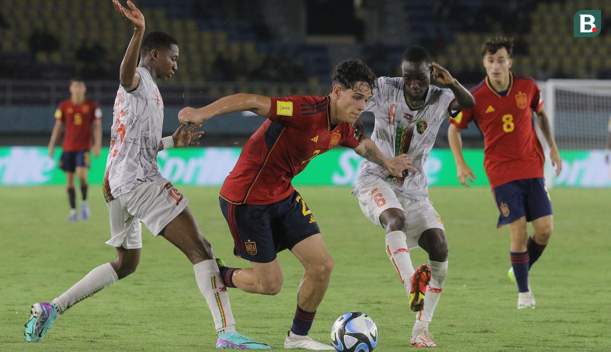 <p>Pemain Timnas Spanyol U-17, Hector Fort (tengah) berusaha melewati hadangan pemain Mali U-17 dalam pertandingan babak penyisihan Grup B Piala Dunia U-17 di Stadion Manahan, Solo. Senin (13/11/2023). (Bola.com/Arief Bagus)</p>