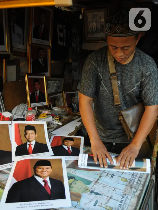 Pedagang bingkai foto bergambar presiden dan wakil presiden terpilih 2024-2029 menata dagangannya di Pasar Baru Jakarta, Senin (22/4/2024). (merdeka.com/Imam Buhori)