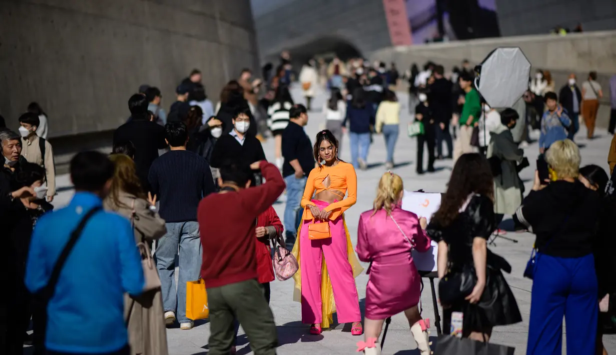 Model AS yang berbasis di Seoul, Jaspreet Kaur (tengah) berpose saat fotografer mengambil foto selama Seoul Fashion Week Spring/Summer 2023 di Dongdaemun Design Plaza di Seoul pada 12 Oktober 2022. (AFP/Anthony Wallace)