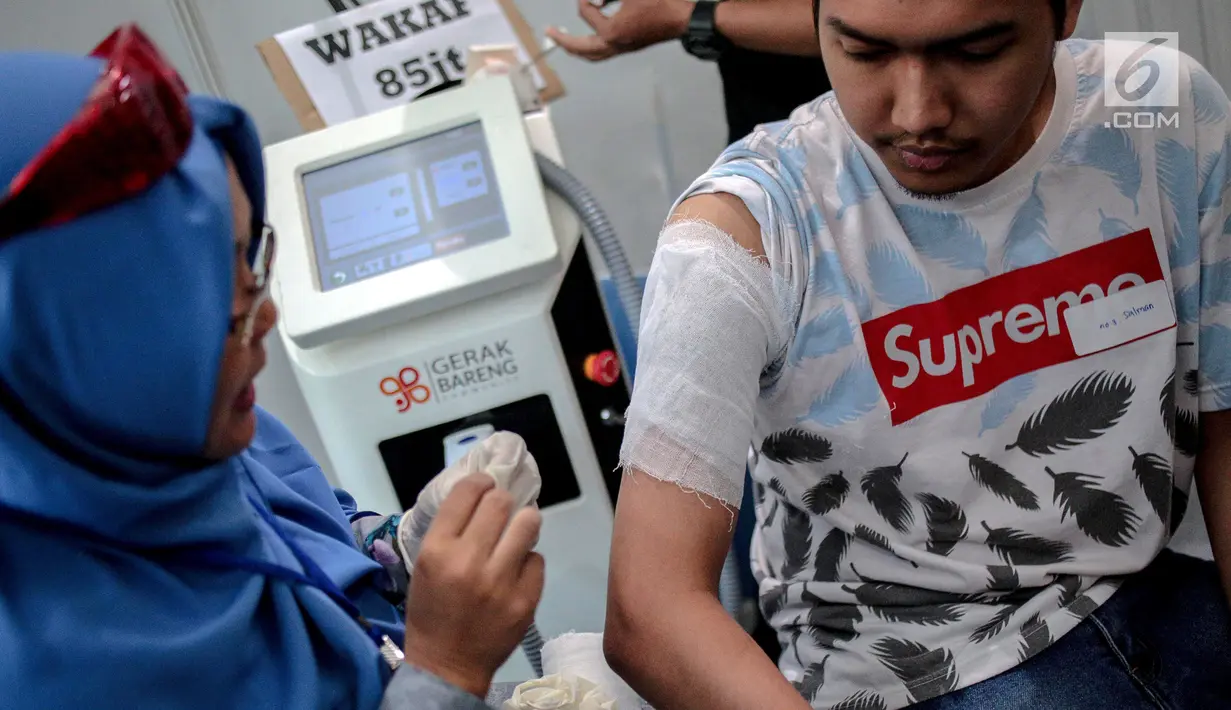 Petugas Komunitas Gerak Bareng menghapus tato dalam Hijrah Fest 2018 di Jakarta, Sabtu (10/11). Selain menyetor hapalan surat Alquran, peserta juga diharuskan menyertakan surat medical check up HIV, diabetes dan hepatitis. (Liputan6.com/Faizal Fanani)