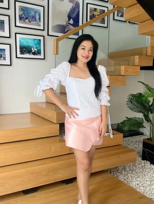 Tampil feminim namun tetap simple dengan atasan lengan 3/4 warna putih. Dipadukan skort pink dan sandal putihnya. [@titi_kamall]