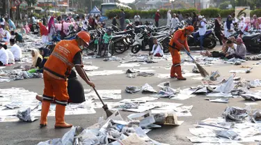 Petugas membersihkan koran usai salat id Hari Raya Idul Fitri 1 Syawal 1439 H di kawasan Senen, Jakarta, Jumat (15/6). Banyaknya koran yang berserakan membuat petugas harus sigap membersihkan agar tidak mengotori jalan. (Liputan6.com/Immanuel Antonius)