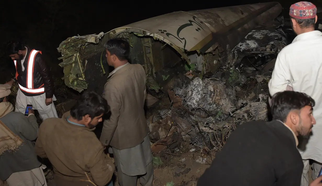 Sejumlah orang mengamati puing pesawat Pakistan International Airlines (PIA) yang jatuh di wilayah Khyber Pakhtunkhawa, Rabu (7/12). Menurut laman PIA, dua berkewarganegaraan Austria dan satu dari China, termasuk sebagai korban tewas. (AAMIR QURESHI/AFP)