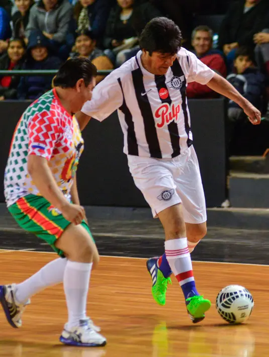 Presiden Bolivia Evo Morales menggiring bola saat pertandingan persahabatan melawan anggota komunitas Bolivia setempat selama kunjungannya di Asunción, Paraguay, (14/8). (AFP Photo/Silvio Rojas)