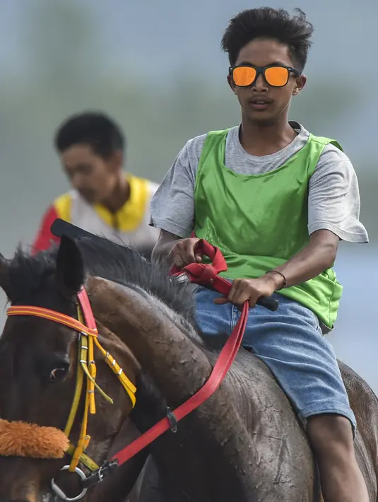 Joki muda saling memacu kuda dalam balapan kuda tradisional di Takengon, provinsi Aceh pada 2 Maret 2019. Pacuan kuda tradisional digelar pada hari-hari besar daerah nasional di dataran tinggi Gayo Aceh. (CHAIDEER MAHYUDDIN/AFP)