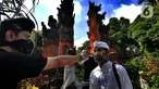 Petugas memeriksa suhu tubuh pengurus Pura Amerta Jati menjelang persiapan Hari Raya Nyepi Saka 1942 di Cinere, Depok, Selasa (24/3/2020). Rangkaian perayaan Nyepi di sejumlah pura hanya akan dilakukan oleh panitia dalam jumlah terbatas untuk mencegah penyebaran Covid-19. (merdeka.com/Arie Basuki)