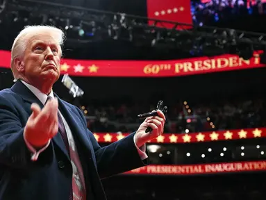 Presiden Amerika Serikat, Donald Trump melemparkan pena ke arah kerumunan setelah menandatangani perintah eksekutif selama parade perdana di dalam Capital One Arena, Washington, DC pada 20 Januari 2025. (Jim WATSON/AFP)