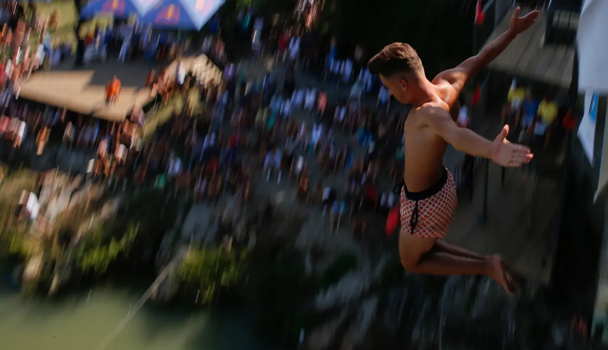 Seorang peserta melakukan terjun bebas dari jembatan Ura e Shejnt dalam kompetisi menyelam tradisional ke-68 di Gjakova, Kosovo, 22 Juli 2018. Kompetisi ini dilakukan dari ketinggian 22 meter. (AP/Visar Kryeziu)