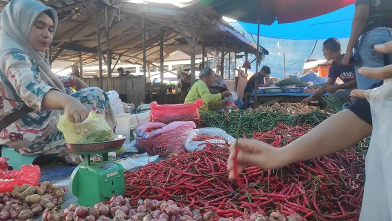 Warga memilih harga cabai merah keriting di pasar tradisional.