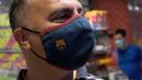 Fans memakai masker berlogo Barcelona di Toko Asesoris Barcelona, Senin (25/5/2020). Di tengah pandemi virus Corona, Barcelona menjual masker dengan harga 18 euro atau sekitar Rp 291 ribu. (AFP/Lluis Gene)