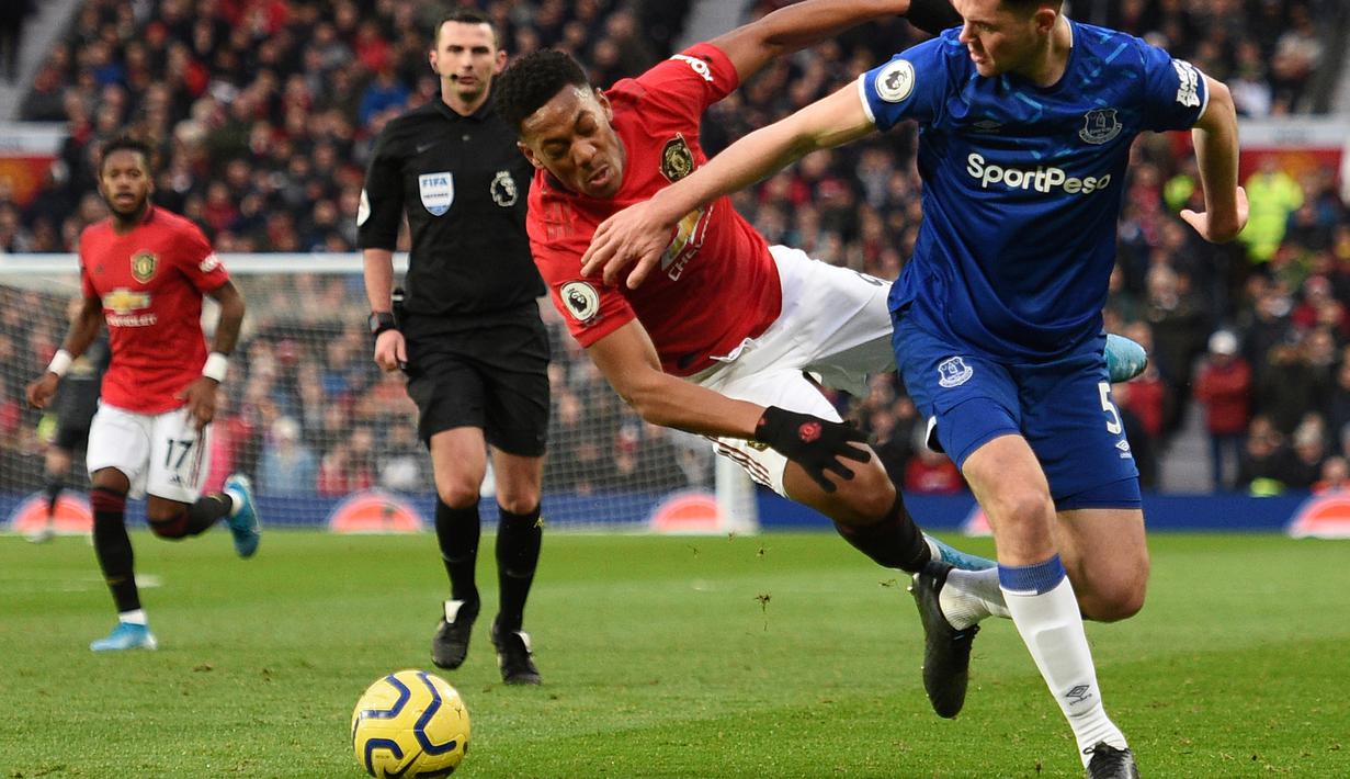 Striker Manchester United, Anthony Martial, berebut bola dengan bek Everton, Michael Keane, pada laga Premier League di Stadion Old Trafford, Manchester, Minggu (15/12). Kedua klub bermain imbang 1-1. (AFP/Oli Scarff)