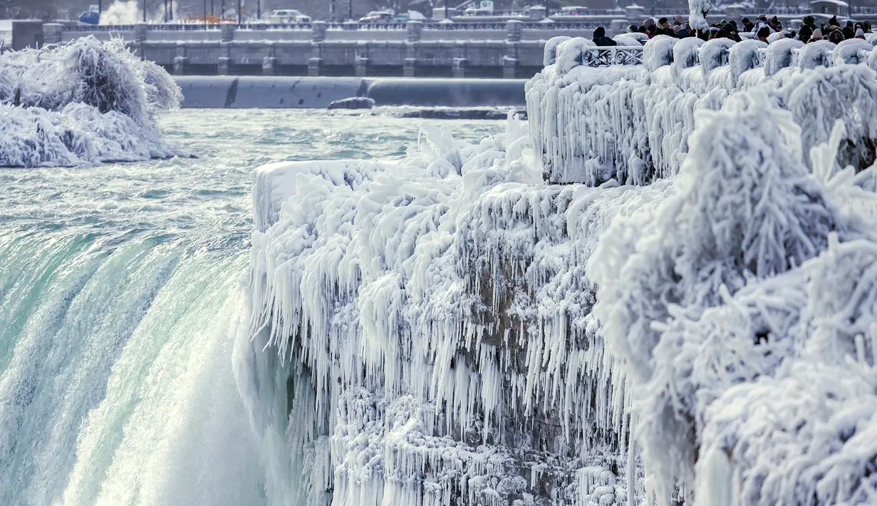 Pengunjung mengambil gambar Horseshoe Falls di Air Terjun Niagara yang membeku di Ontario, Kanada, Jumat (29/12). Cuaca dingin melanda sebagian besar wilayah utara Amerika Serikat di akhir tahun ini. (Aaron Lynett/Canadian Press via AP)