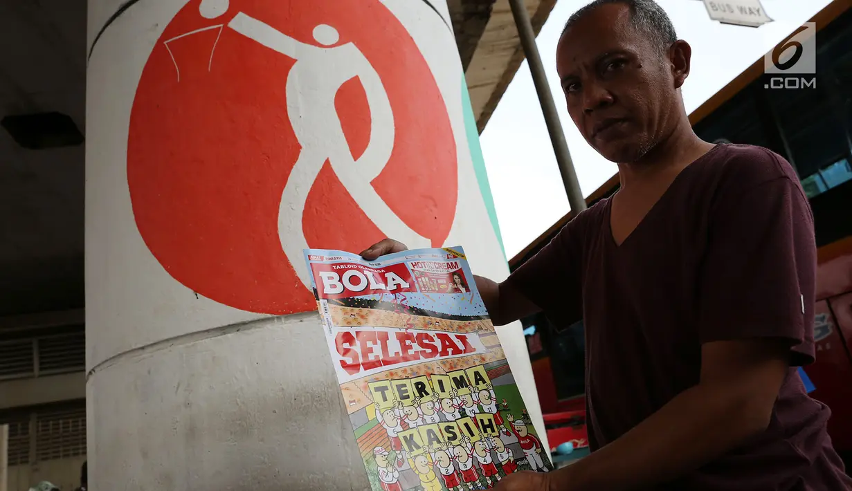 Pedagang menunjukkan tabloid Bola di Terminal Kampung Melayu, Jakarta, Jumat (26/10). Tabloid Bola mengucapkan salam perpisahan. (Merdeka.com/Imam Buhori)