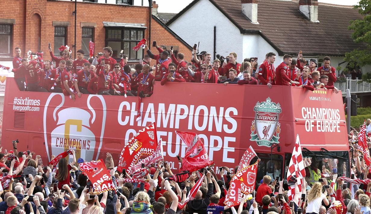 Para pemain Liverpool menyapa fans saat parade juara Liga Champions 2019 di Liverpool, Minggu (2/6). Ribuan fans tumpah ruah di jalanan untuk merayakan keberhasilan pemain membawa pulang trofi Si Kuping Besar ke kota Liverpool. (AP/Barrington Coombs)