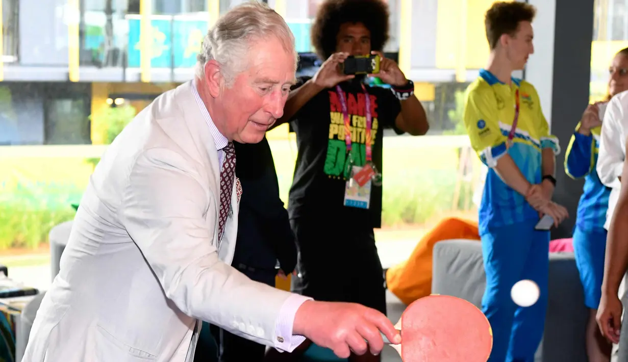 Pangeran Charles memukul bola saat bermain tenis meja selama kunjungannya ke desa atlet Goldwe Common Games 2018 di Gold Coast (5/4). Dalam kunjungannya Pangeran Charles ditemani sang istri Camilla Parker. (AFP Photo/Pool/William West)