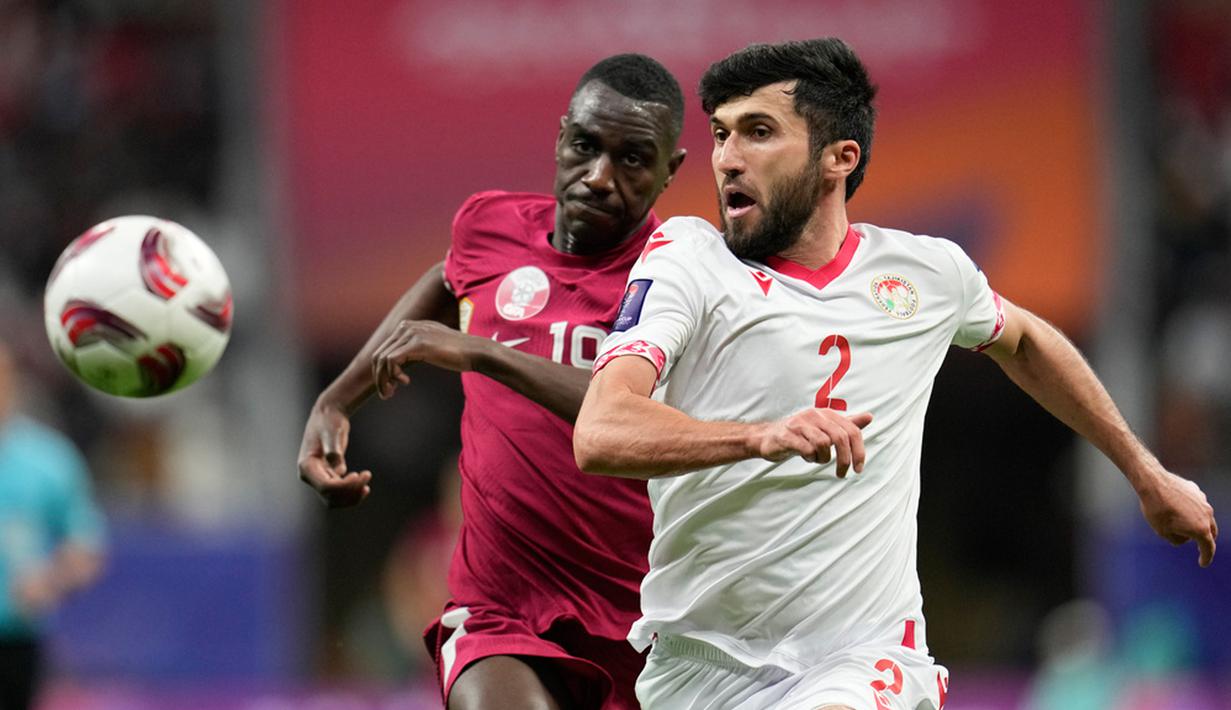 Pemain Tajikistan Zoir Dzhuraboev (kanan) dan pemain Qatar Almoez Ali berlari mengejar bola pada pertandingan sepak bola Grup A Piala Asia di Stadion Al Bayt, Al Khor, Qatar, Rabu (17/1/2024). (AP Photo/Aijaz Rahi)