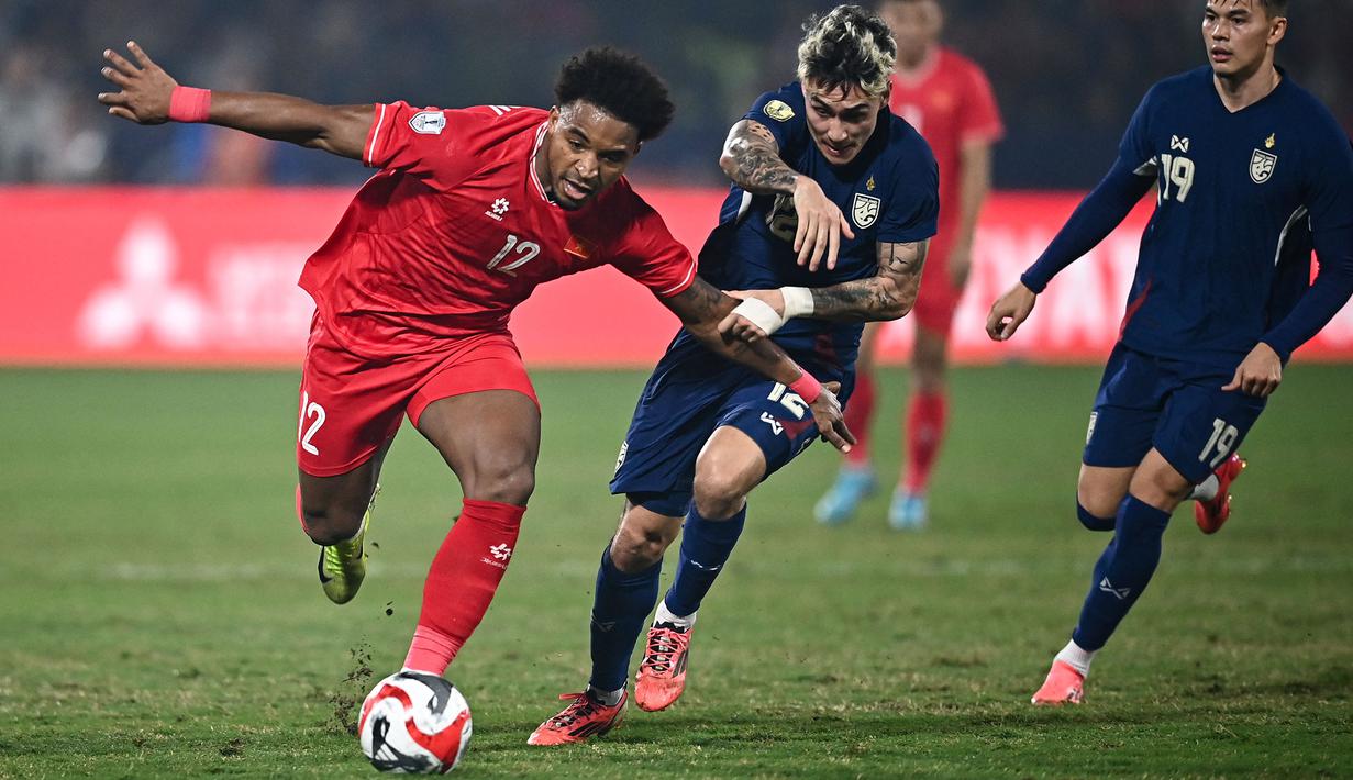 <p>Pemain naturalisasi baru Vietnam, Nguyen Xuan Son (kiri) menggiring bola melewati pemain Thailand, Nicholas Mickelson dalam laga leg pertama final Piala AFF 2024 yang berlangsung di Viet Tri Stadium, Vietnam, Selasa (02/01/2025) waktu setempat. (AFP/Nhac Nguyen)</p>