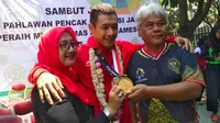 Pesilat peraih medali emas Asian Games 2018, Hanifan Yudani Kusumah, diapit kedua orang tua. (Bola.com/Erwin Snaz)