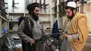 Seorang pedagang senjata Hakimullah Afridi (kiri) memperlihatkan senapan otomatis buatan lokal kepada pelanggan di tokonya, Darra Adamkhel, Pakistan, 14 Desember 2022. Kota Darra Adamkhel telah lama dikenal dengan bazar pasar gelap senjatanya. (Abdul MAJEED/AFP)