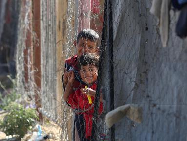 Anak-anak berdiri di samping tenda-tenda di kamp yang menampung para pengungsi Palestina di kamp Al-Bureij, Jalur Gaza tengah pada 7 Juli 2025. (Eyad BABA/AFP)