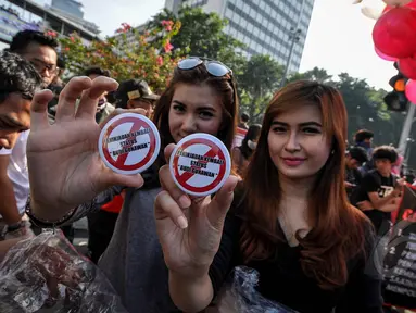 Sejumlah perempuan cantik menunjukkan pin bertuliskan "peninjauan kembali status Budi Gunawan" saat menggelar aksi di Bundaran HI, Minggu (4/4/2015). Padahal, Pemprov DKI melarang adanya kegiatan bernuansa politik saat CFD. (Liputan6.com/Faizal Fanani)